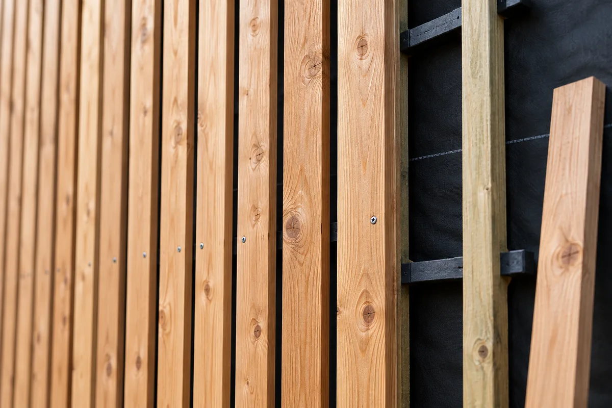 Lames de douglas verticales vissées sur tasseaux devant un pare-pluie noir